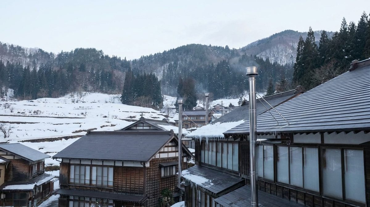 雪の山あいの町に並ぶ煙突のある家々